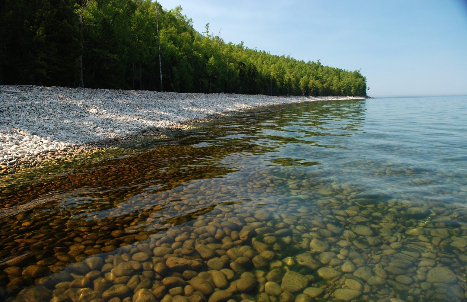 Прозрачная вода озера Байкал и скала Шаманка